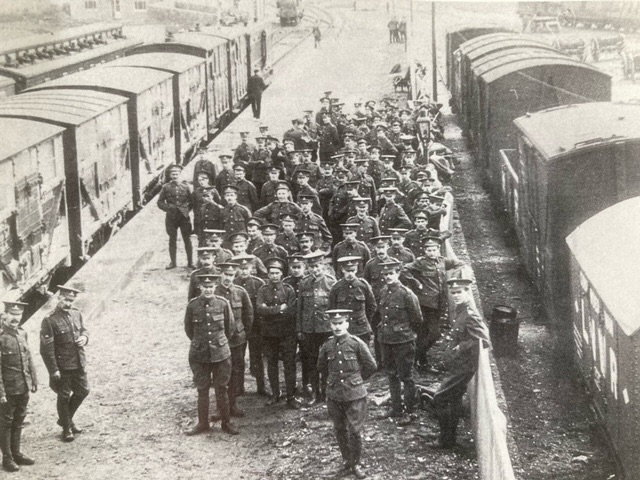 Black and white photo of uniformed men stood by a train