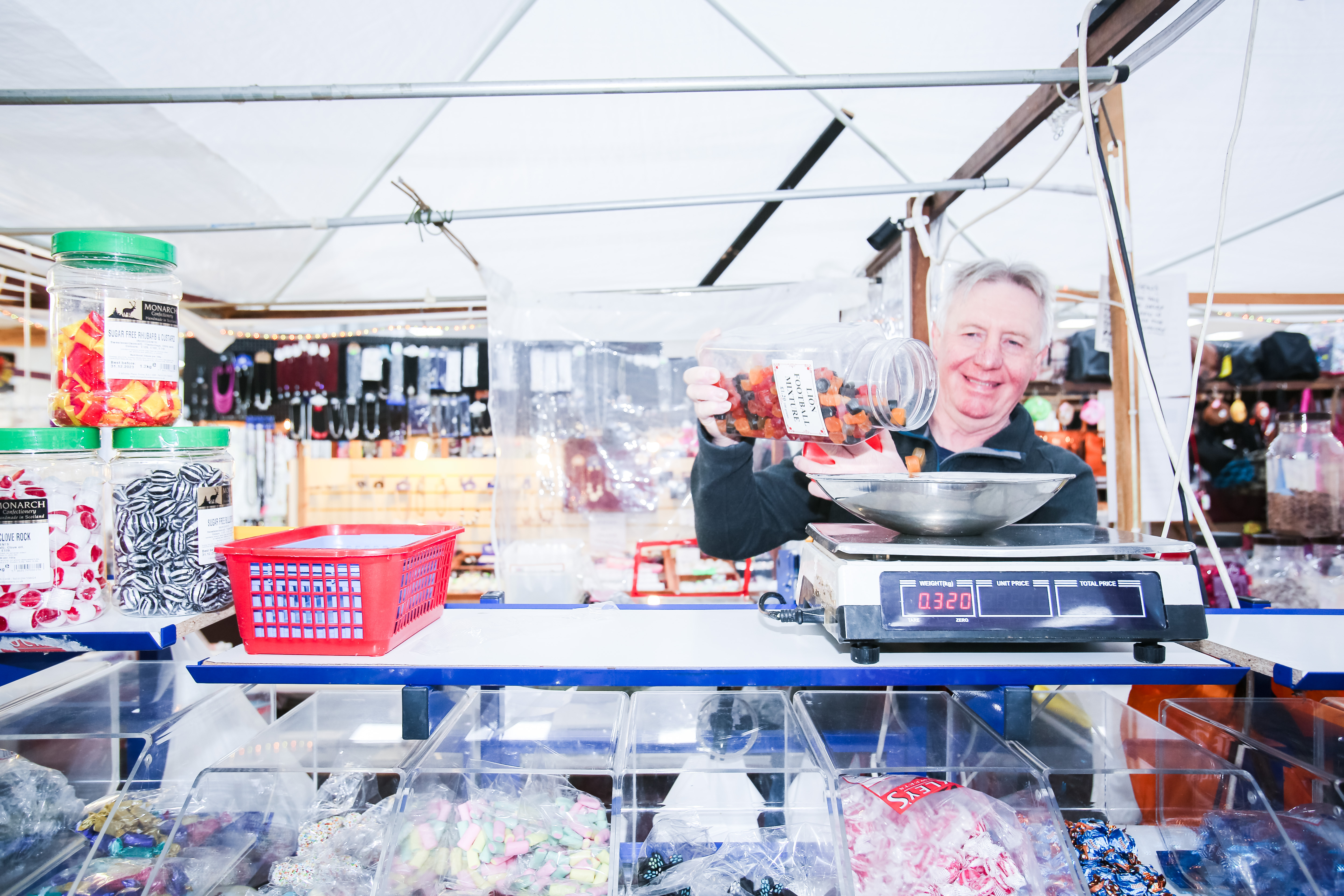 Man serving confectionary at market sweet stall