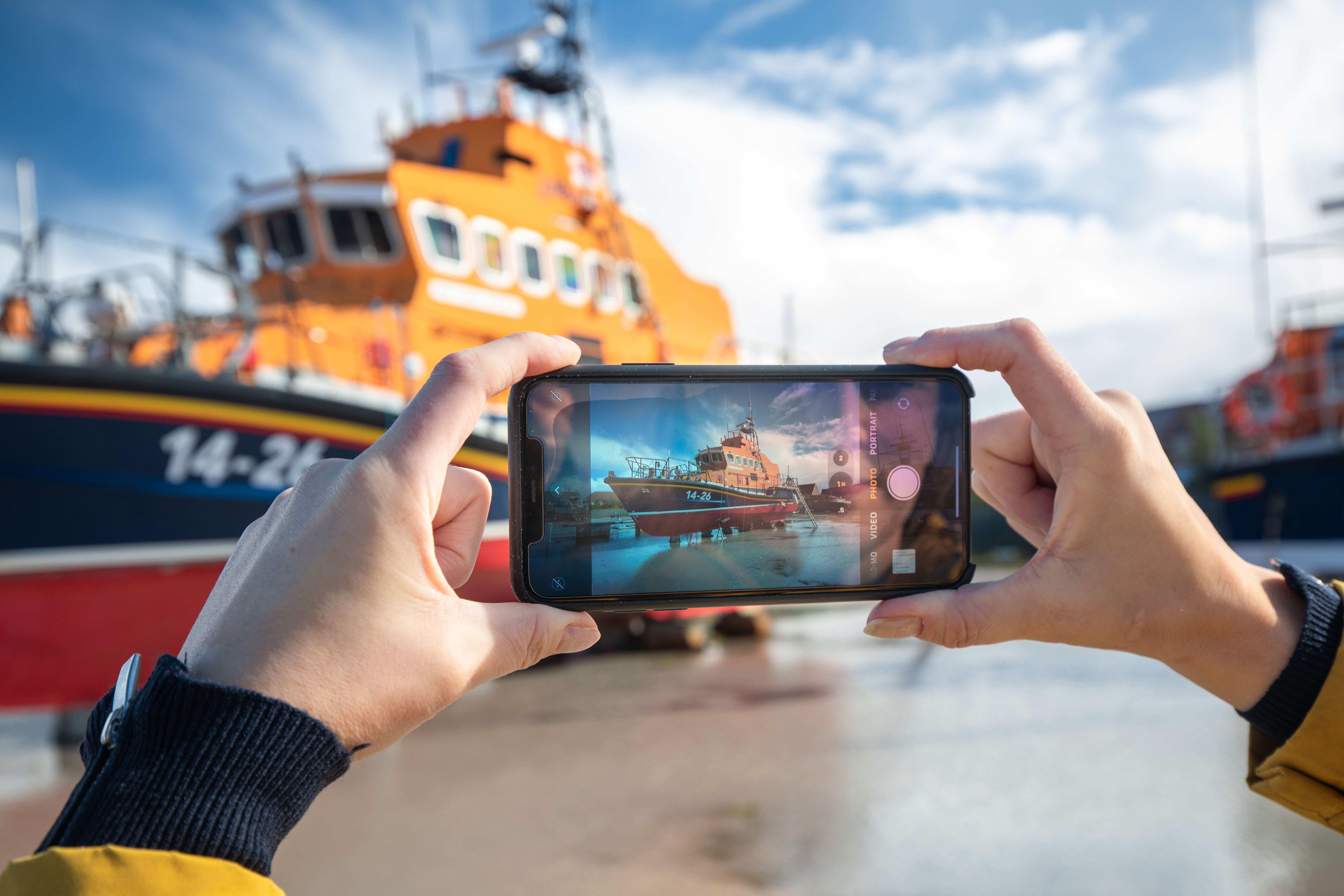 Hand holding phone taking photo of an RNLI lifeboat