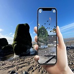 Hand holding mobile phone over stone ogre