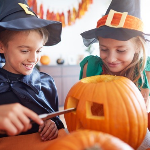 Children carving pumpkins dressed as witches