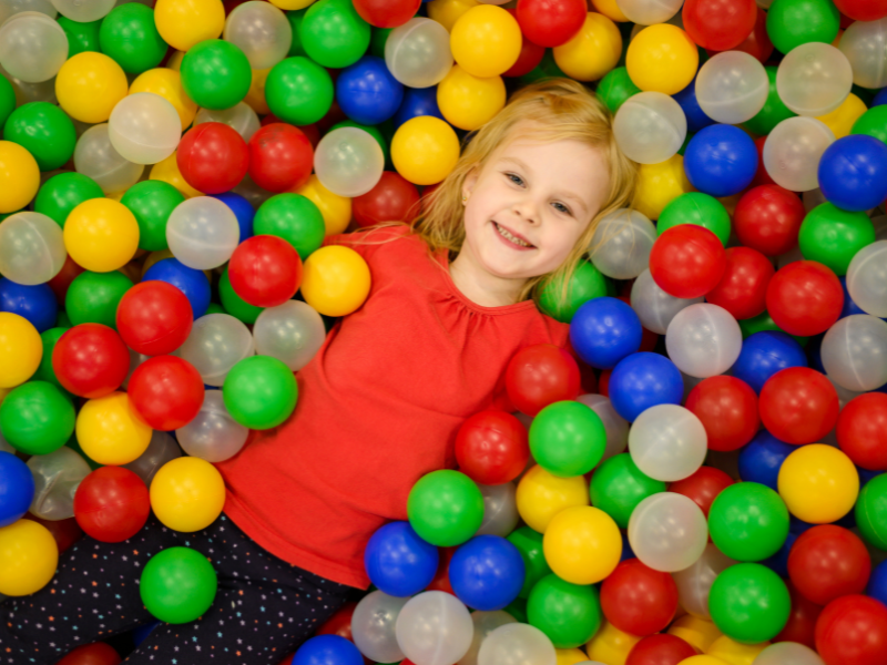 Young girl lying down in ball pool