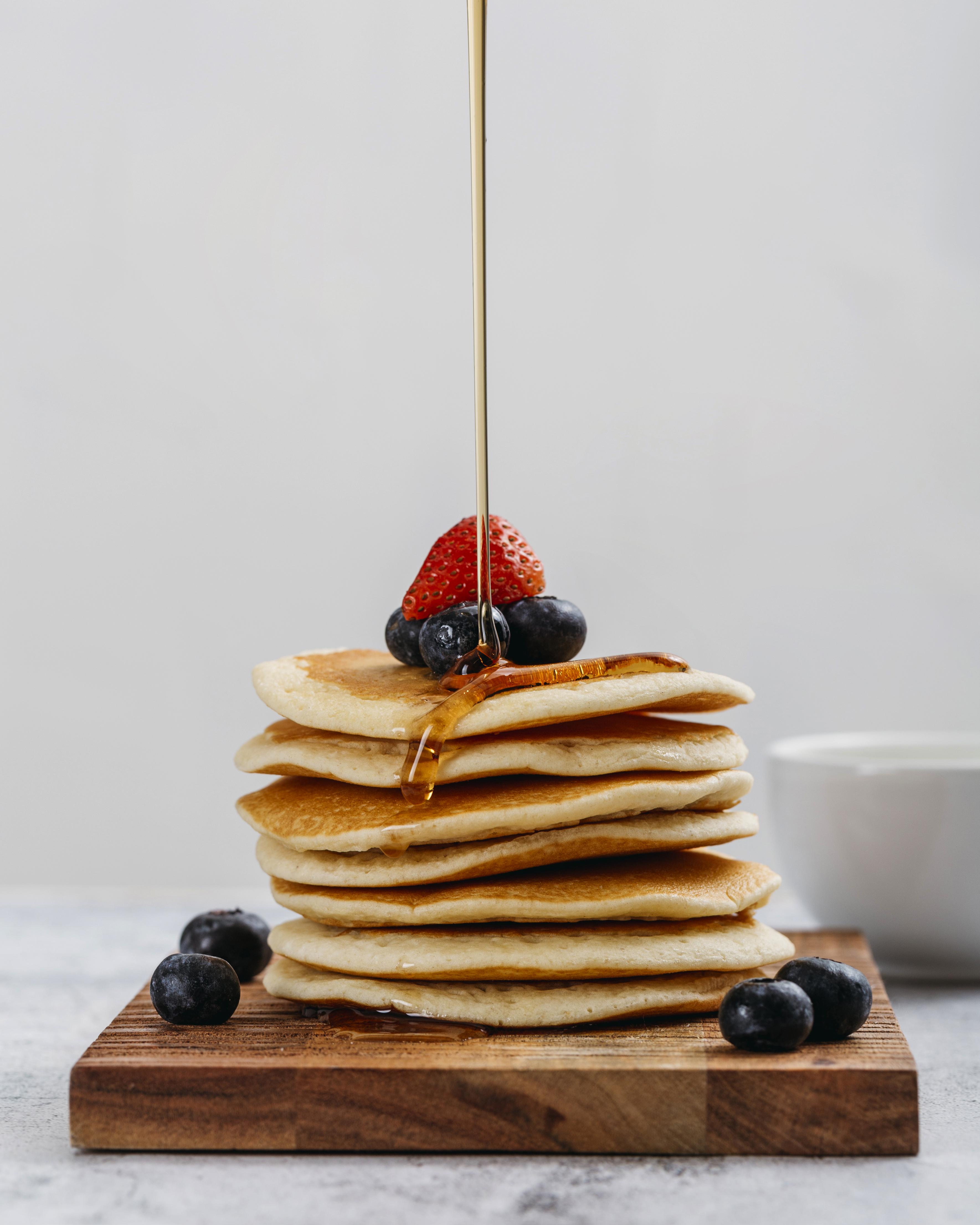 stack on pancakes with fruit and honey poured over