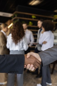People shaking hands with people behind them at business event